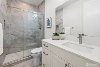 Upgraded main bathroom enhanced beyond builder finishes, featuring a floor-to-ceiling tiled walk-in shower, quartz countertops, and a spa-inspired design that elevates everyday living in this newer construction McCormick Trails home.
