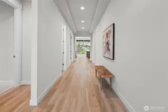 View from the front entry hallway revealing a straight sightline to the landscaped backyard, highlighting durable flooring, natural light, and the welcoming open layout of this upgraded newer construction home in McCormick Trails, Port Orchard.