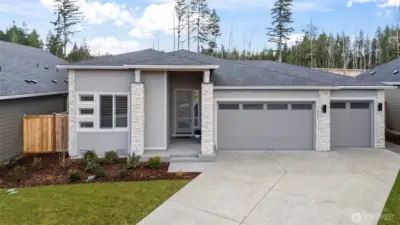 Front exterior view showcasing the spacious three-car garage and modern architectural design, highlighting the curb appeal of this upgraded newer construction home in McCormick Trails, Port Orchard.