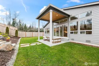 Covered patio view showcasing the dramatic wall of windows that connects indoor and outdoor living, complemented by an efficient heat pump system providing comfortable heating and air conditioning year-round in this upgraded McCormick Trails home.