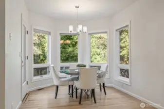 The adjacent informal dining area with walls of windows overlooks the east facing yard.