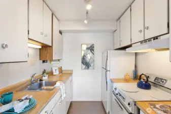 Compact and efficient, this galley kitchen keeps everything close—clean mid-century cabinetry, warm counters, and plenty of storage for everyday cooking.