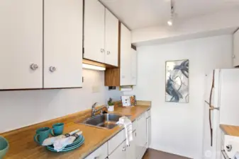 Compact and efficient, this galley kitchen keeps everything close—clean mid-century cabinetry, warm counters, and plenty of storage for everyday cooking.