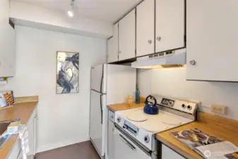 Compact and efficient, this galley kitchen keeps everything close—clean mid-century cabinetry, warm counters, and plenty of storage for everyday cooking.