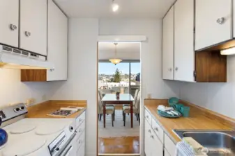 Compact and efficient, this galley kitchen keeps everything close—clean mid-century cabinetry, warm counters, and plenty of storage for everyday cooking.