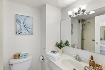The bathroom is clean and bright, with a long vanity, generous mirror, and a classic tiled shower surround.