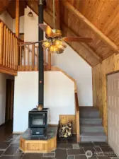 Slate floors surround the entrance, wood stove and leading to the upstairs loft and primary bedroom.