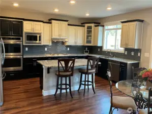 Chef's Kitchen with custom cabinetry, 5-burner gas stove, slab granite counters & double ovens