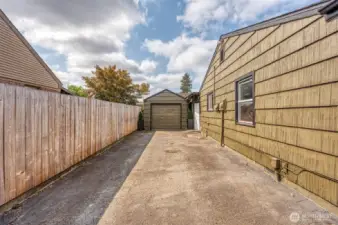 Extended driveway and parking space inside gate, garage at the rear.