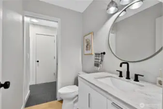 Guest bathroom on main level with separate shower and mudroom space, Door leads to exterior deck with hot tub.