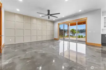 Lower living room with custom wood wall & fan with slider to backyard with water toy garage