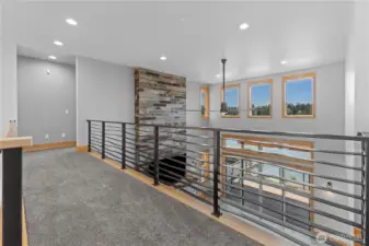 Catwalk with custom iron railings between 2 primary suites on 2nd floor. Looks down to Living Room/Great room below.