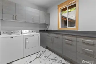 Laundry room on 2nd floor with tons of drawers and cabinets plus a sink and built-in trash can.