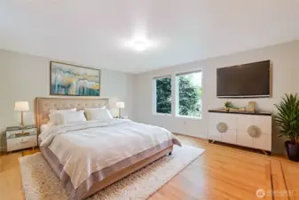 A look at the virtually staged, lower-level primary bedroom. Note the hardwood floors and the accent detail wood on them. This private bedroom has multiple closets, including a walk-in closet, and a spacious bathroom.