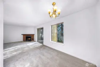 A large dining and living area with a wood-burning fireplace. The sliding glass door opens to a southeast-facing balcony with a territorial view.