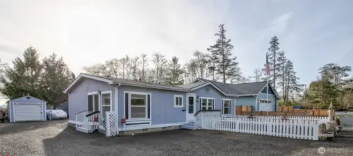 The side door enters into the kitchen, and behind the home is the shed, studio ADU, and an additional garage, along with RV hookups and parking.