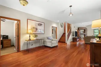 A large open area looks toward the living room and fireplace. An office is just inside the front entrance.