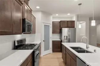 Beautiful charcoal-stained maple cabinets and quartz countertops throughout the home. A walk-in pantry in the heart of the kitchen for all your kitchen needs.