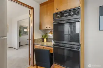 Double ovens offer added cooking capacity, ideal for gatherings and holiday meals. A built-in workspace nearby provides a spot for planning recipes or keeping the chef company.