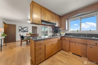 This kitchen features wood cabinetry, granite countertops, and a sizeable window above the sink with backyard views. The adjacent dining area and eating space create a functional layout for daily living and entertaining.