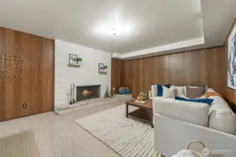 The family room features a classic wood-burning fireplace set against a block accent wall, adding warmth and character. Timeless wood paneling pairs beautifully with the neutral tones throughout the space for a welcoming and grounded atmosphere.