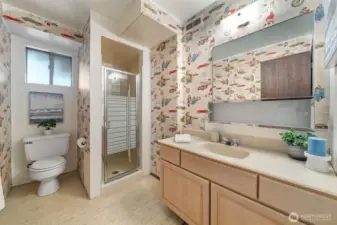 The lower-level main bath includes easy-care flooring, a classic vanity, a built-in medicine cabinet, and an easy-care shower surround.