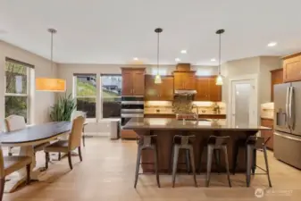 Gourmet kitchen designed for gathering features a Wolf range with upgraded hood, double ovens, upgraded counters, center island with large bar, and rich engineered hardwood floors. Open to the dining area and great room, this layout keeps everyone connected while offering both beauty and functionality.