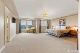 Private primary suite retreat features a double door entry, comfortable sitting area, abundant natural light, partial valley and territorial views, coved ceiling, and walk-in closet. Thoughtfully positioned for privacy, it offers a peaceful escape at the end of the day.