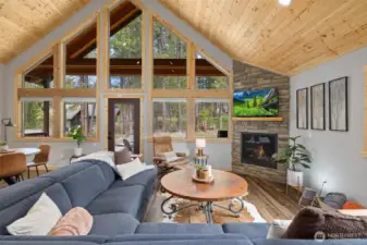 Soaring tongue-and-groove ceilings and a floor-to-ceiling rock fireplace create a warm, inviting cabin atmosphere.