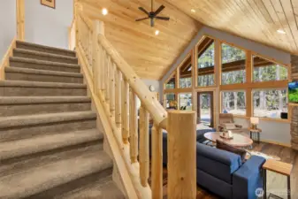 The stairway to the upper-level bunk room is accented with a rustic log railing, adding character and charm.