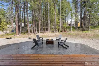 An oversized concrete patio, equipped with a custom propane firepit, provides the perfect space for relaxation and entertaining throughout the year.