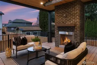 Covered outdoor living space centered around a stunning fireplace, offering a warm and inviting setting for relaxing or entertaining year-round.
