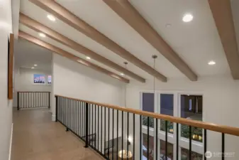 Mezzanine-style upper walkway overlooking the dining area, featuring exposed beams and open railings that enhance light and connection.