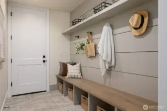 Thoughtfully appointed mudroom with custom built-ins, bench seating, and overhead storage offers a seamless transition from garage to home.