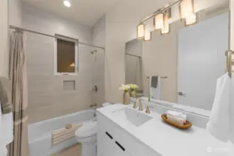 First floor bathroom with white quartz vanity and a bathtub.
