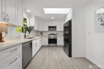 Fully remodeled kitchen with white shaker cabinets, quartz countertops, an industrial sink with matte black faucet, new skylight and all new appliances