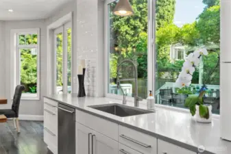 A picturesque window over the sink frames the patio and blooming garden.