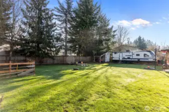 Flat lawn bordered by mature trees, creating a private and peaceful outdoor setting.