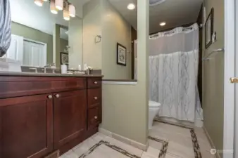 Guest bath with tile floors and decorative glass inlays. Vanity offers quartz countertops