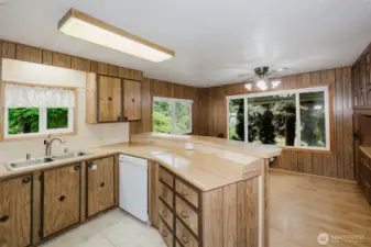 There is a lot of storage and workspace in this kitchen.  Breakfast bar and dining area beyond, with built-ins on both sides.