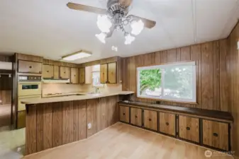 View of the kitchen from the dining area, showing the breakfast bar and just a part of the built-in storage in that room.