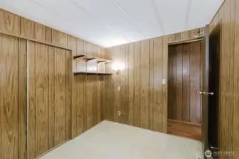 This view of bedroom #2 includes the closet door, wall shelves and the door to the hallway.