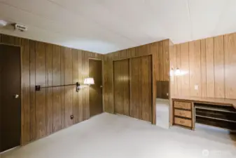 Primary bedroom with door to hallway at the left, and the door to the bathroom in the center.