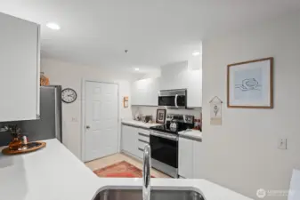 White quartz counters, updated stainless appliances, fixtures and great lighting in this remodeled kitchen. The door leads to the garage. So convenient!