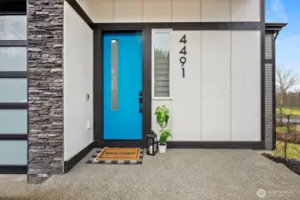 Modern exterior of a contemporary home for sale in the River Rock subdivision, featuring clean architectural lines, stone accents, a spacious driveway, and attached garage. Aerial and front views highlight its setting within the scenic River Rock community surrounded by natural greenery.