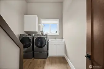 Laundry area in this River Rock home features a dedicated space with washer and dryer, upper cabinetry, and natural light from the window. The clean layout and built in storage create a practical and convenient laundry setup for everyday living.