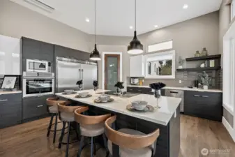 This modern kitchen features a large center island with seating, sleek cabinetry, and stainless appliances that create a stylish and highly functional cooking space. The open concept layout connects naturally to the surrounding living areas, making it ideal for entertaining and everyday living.