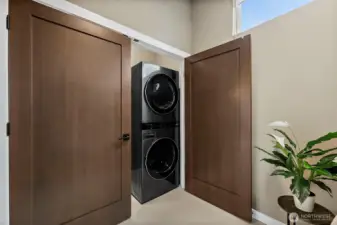 Laundry area in this River Rock home features a dedicated space with washer and dryer, upper cabinetry, and natural light from the window. The clean layout and built in storage create a practical and convenient laundry setup for everyday living.