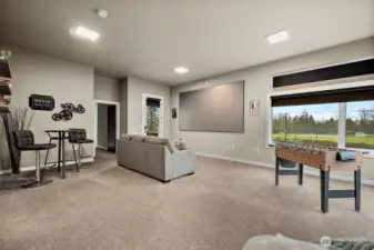 This lower level rec room creates a flexible entertainment space with room for a media area, games, and casual seating. Large windows bring in natural light while the open layout allows the room to function as a comfortable gathering space.