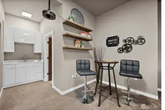 Spacious lower level entertainment room in this River Rock home in Auburn featuring a projector, large screen, wet bar, and comfortable seating areas. With direct patio access, this versatile rec room is designed for movie nights, hosting guests, and seamless indoor outdoor entertaining.